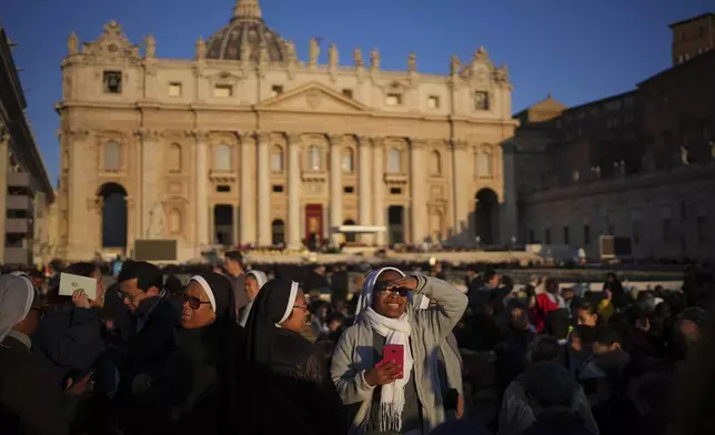 A nun smiles as she waits ahead of the funeral of Pope Francis in St. Peter's Square at the Vatican, Saturday, April 26, 2025. (AP Photo/Emilio Morenatti)