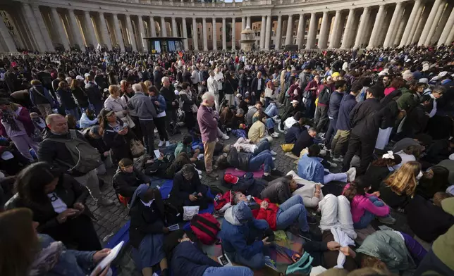Faithful rest on the ground ahead of the funeral of Pope Francis in St. Peter's Square at the Vatican, Saturday, April 26, 2025. (AP Photo/Andrew Medichini)