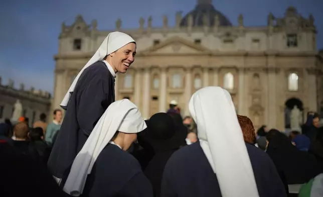 Nuns share a laugh as people gather for the funeral of Pope Francis in St. Peter's Square at the Vatican, Saturday, April 26, 2025. (AP Photo/Andreea Alexandru)