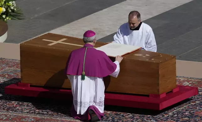Archbishop Diego Giovanni Ravelli, back to camera, kneels by the coffin of Pope Francis in St. Peter's Square at the Vatican, Saturday, April 26, 2025. (AP Photo/Gregorio Borgia)