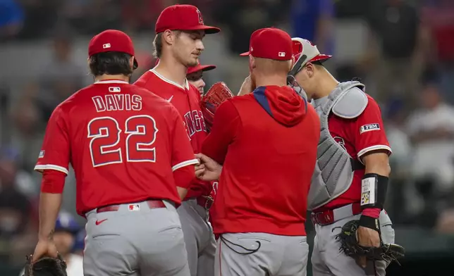 Los Angeles Angels players gather around starting pitcher Jack Kochanowicz, center, for a mound visit during the second inning of a baseball game against the Texas Rangers Thursday, April 17, 2025, in Arlington, Texas. (AP Photo/Julio Cortez)