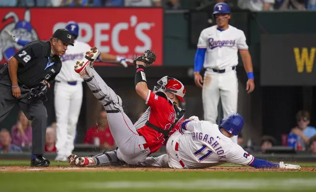 Texas Rangers' Kyle Higashioka (11) is tagged out at home by Los Angeles Angels catcher Logan O'Hoppe while trying to score on a two-run double by Leody Taveras during the second inning of a baseball game Thursday, April 17, 2025, in Arlington, Texas. (AP Photo/Julio Cortez)