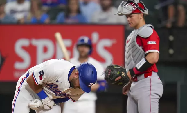 Texas Rangers' Jake Burger, left, reacts after being hit by a pitch as Los Angeles Angels catcher Logan O'Hoppe looks on during the second inning of a baseball game Thursday, April 17, 2025, in Arlington, Texas. (AP Photo/Julio Cortez)