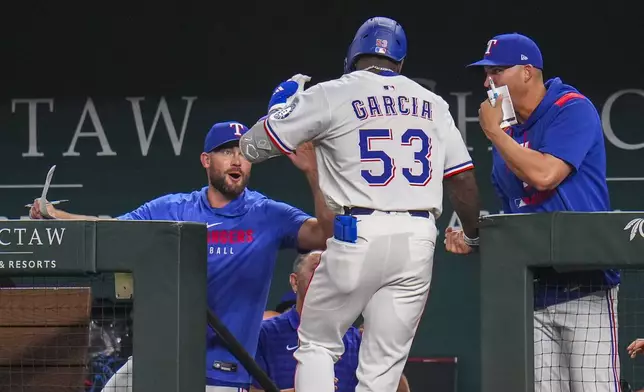 Texas Rangers' Adolis García (53) is greeted by teammates after hitting a home run off Los Angeles Angels starting pitcher Jack Kochanowicz during the third inning of a baseball game Thursday, April 17, 2025, in Arlington, Texas. (AP Photo/Julio Cortez)