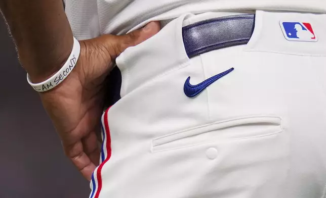 Texas Rangers third base coach Tony Beasley wears a message on a bracelet during the fourth inning of a baseball game against the Los Angeles Angels Thursday, April 17, 2025, in Arlington, Texas. (AP Photo/Julio Cortez)