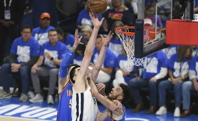 Memphis Grizzlies center Zach Edey, middle, shoots over Oklahoma City Thunder center Isaiah Hartenstein, left, and forward Chet Holmgren, right, during the first half in Game 1 of an NBA first-round playoff series, Tuesday, April 22, 2025, in Oklahoma City. (AP Photo/Kyle Phillips)