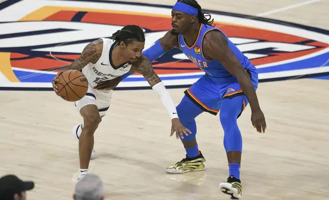 Memphis Grizzlies guard Ja Morant, left, drives past Oklahoma City Thunder guard Luguentz Dort, right, during the first half in Game 1 of an NBA first-round playoff series, Tuesday, April 22, 2025, in Oklahoma City. (AP Photo/Kyle Phillips)