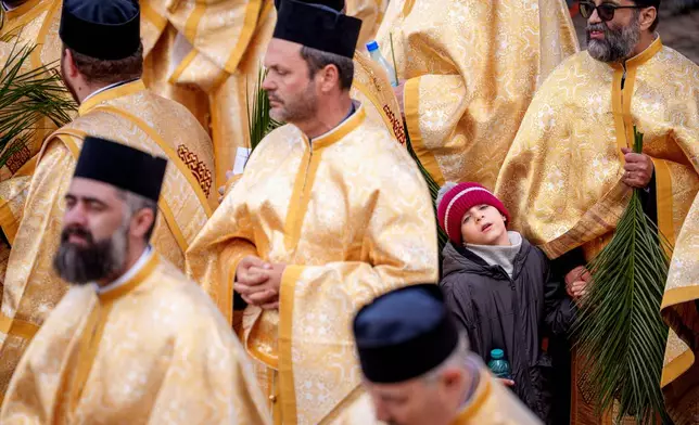 A child stands among priests outside the Patriarchal Cathedral after an Orthodox Palm Sunday pilgrimage in Bucharest, Romania, Saturday, April 12, 2025. (AP Photo/Andreea Alexandru)