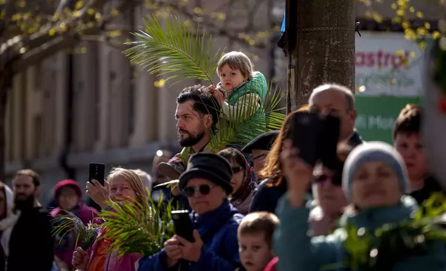 A child watches Romanian Orthodox priests and believers walk during an Orthodox Palm Sunday pilgrimage in Bucharest, Romania, Saturday, April 12, 2025. (AP Photo/Andreea Alexandru)