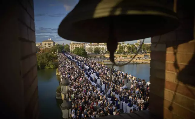 Penitents of the Estrella brotherhood walk in procession across the so-called Triana bridge during Holy Week in Seville., Spain, Sunday, April 13, 2025. Hundreds of processions take place throughout Spain during the Easter Holy Week. (AP Photo/Emilio Morenatti)