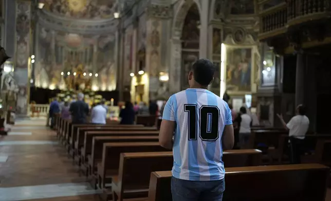A man wearing an Argentina soccer jersey prays at the Santo Spirito in Sassia Church, Sanctuary of the Divine Mercy, in Rome, Tuesday, April 22, 2025. (AP Photo/Bernat Armangue)