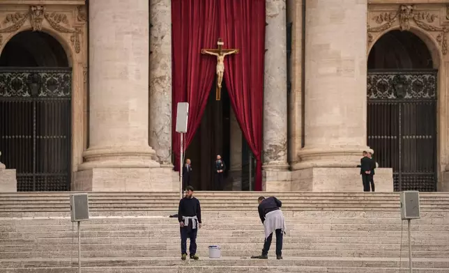 Men wash the steps St. Peter's Basilica before the arrival of the body of Pope Francis, who will lie in state at for three days, at the Vatican, Wednesday, April 23, 2025. (AP Photo/Andreea Alexandru)