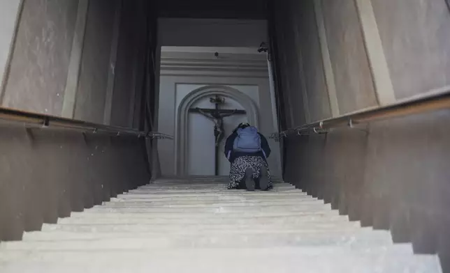 A pilgrim kneels in prayer on the Scala Santa, holy stairs, of the Church of Church of Saints Michael and Magnus, in Rome near the Vatican, Tuesday, April 22, 2025. (AP Photo/Andrew Medichini)