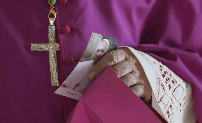 A prelate holds a picture of Pope Francis as he enters the atrium of St. Peter's Basilica at the Vatican, Wednesday, April 23, 2025, where the body of Pope Francis will lie in state for three days. (AP Photo/Andrew Medichini, Pool)