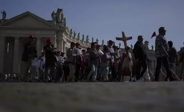Pilgrims carrying a cross make their way to the Holy Door in St. Peter's Square at the Vatican after Cardinal Camerlengo Kevin Joseph Farrell announced the death of Pope Francis, Monday, April 21, 2025. (AP Photo/Alessandra Tarantino)