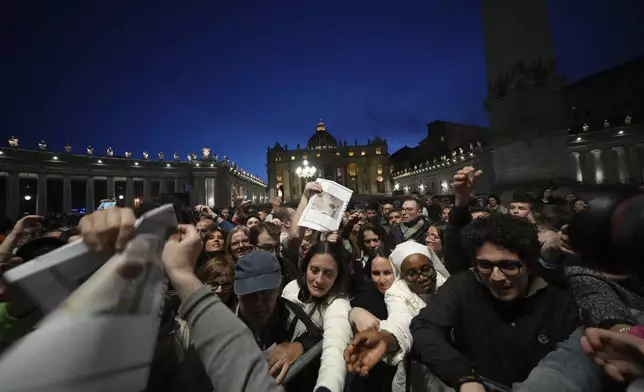 Copies of the Vatican paper L'Osservatore Romano are distributed after a rosary prayer for the late Pope Francis, in St. Peter's Square at the Vatican, Monday April 21, 2025. (AP Photo/Alessandra Tarantino)