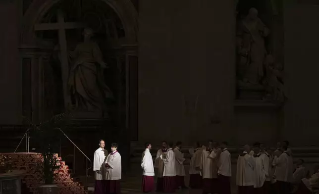 Priests in St. Peter's Basilica wait for the arrival of the body of Pope Francis, who will lie in state for three days, at the Vatican, Wednesday, April 23, 2025. (AP Photo/Francisco Seco)