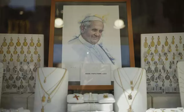 A portrait of Pope Francis with a message below it reading in Italian "Farewell Pope Francis", is seen in the window of a religious jewellery shop, near the Vatican, Tuesday, April 22, 2025. (AP Photo/Andrew Medichini)