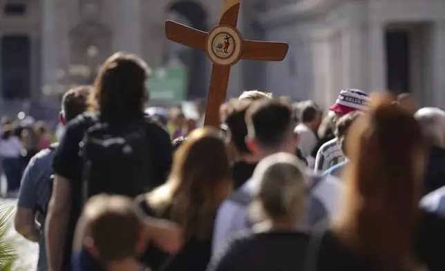 Pilgrims carrying a cross make their way to the Holy Door in St. Peter's Square at the Vatican after Cardinal Camerlengo Kevin Joseph Farrell announced the death of Pope Francis, Monday, April 21, 2025. (AP Photo/Andrew Medichini)