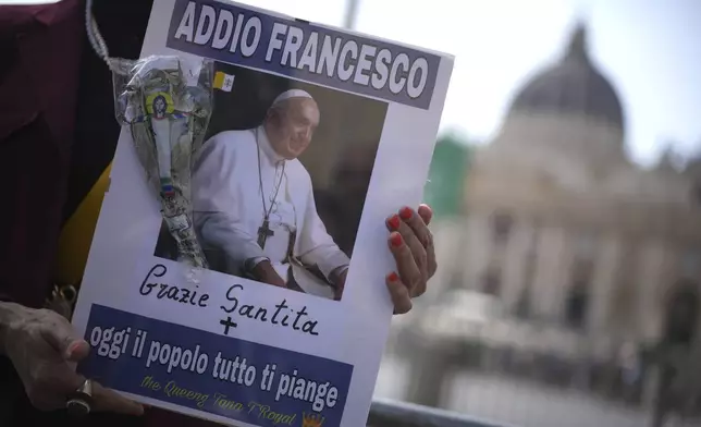 A woman holds a picture of Pope Francis reading in Italian "Farewell Francis, thank you His Holiness, today all the people cry for you" in St. Peter's Square at the Vatican after Cardinal Camerlengo Kevin Joseph Farrell announced the death of Pope Francis, Monday, April 21, 2025. (AP Photo/Andrew Medichini)