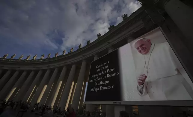 A giant screen announces a rosary prayer for the late Pope Francis in St. Peter's Square at the Vatican, Monday, April 21, 2025. (AP Photo/Andrew Medichini)