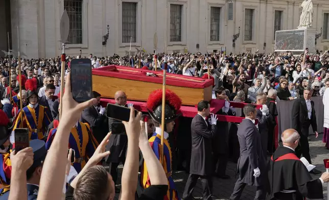 The ceremony with the Pope Francis' body, who will lie in state at St. Peter's Basilica for three days, pass through the crowd at the Vatican, Wednesday, April 23, 2025. (AP Photo/Bernat Armangue)
