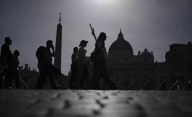 Pilgrims carry a cross in St. Peter's Square at the Vatican after Cardinal Camerlengo Kevin Joseph Farrell announced the death of Pope Francis, Monday, April 21, 2025. (AP Photo/Alessandra Tarantino)