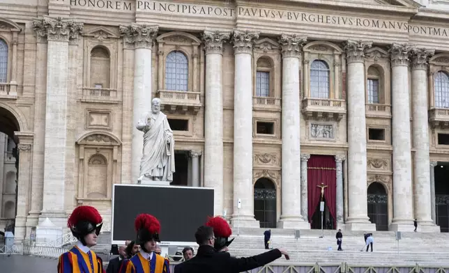 Vatican Swiss Guards receive instructions by a security person in St. Peter's Square ahead of the arrival of the body of Pope Francis, who will lie in state at St. Peter's Basilica for three days, at the Vatican, Wednesday, April 23, 2025. (AP Photo/Gregorio Borgia)
