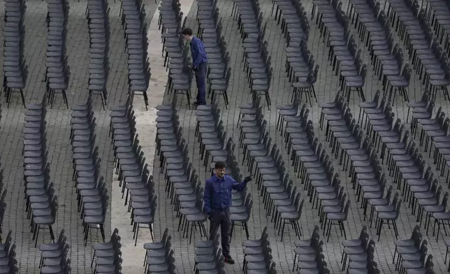 Workers adjust chairs during the preparations in St. Peter's Square ahead of the arrival of the body of Pope Francis, who will lie in state at St. Peter's Basilica for three days, at the Vatican, Wednesday, April 23, 2025. (AP Photo/Gregorio Borgia)