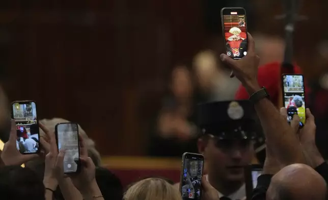 Faithful take pictures with their smartphones as they pay their respects to Pope Francis inside St. Peter's Basilica at the Vatican, Wednesday, April 23, 2025, where his body will lie in state for three days. (AP Photo/Gregorio Borgia)