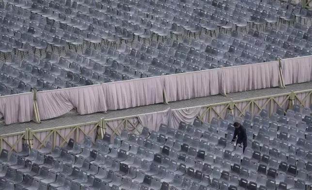 A worker adjusts chairs during the preparations in St. Peter's Square ahead of the arrival of the body of Pope Francis, who will lie in state at St. Peter's Basilica for three days, at the Vatican, Wednesday, April 23, 2025. (AP Photo/Gregorio Borgia)