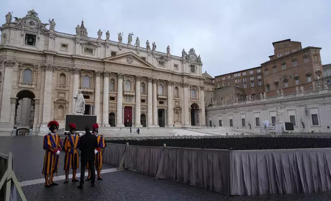 Vatican Swiss Guards receive instructions by a security person in St. Peter's Square ahead of the arrival of the body of Pope Francis, who will lie in state at St. Peter's Basilica for three days, at the Vatican, Wednesday, April 23, 2025. (AP Photo/Gregorio Borgia)