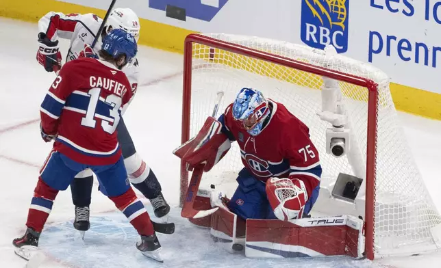 Washington Capitals' Connor McMichael (24) watches as the puck goes through the pads of Montreal Canadiens goaltender Jakub Dobes (75) for the game-tying goal by teammate Brandon Duhaime (not shown) during the third period of Game 4 in an NHL hockey first-round playoff series in Montreal, Sunday, April 27, 2025. (Christinne Muschi/The Canadian Press via AP)