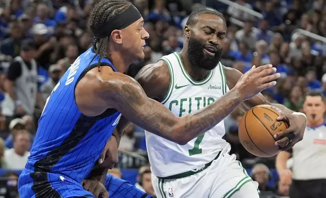 Boston Celtics guard Jaylen Brown, right, makes a move to the basket against Orlando Magic forward Paolo Banchero during the first half in Game 4 of a first-round NBA basketball playoff series, Sunday, April 27, 2025, in Orlando, Fla. (AP Photo/John Raoux)