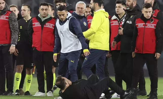 Galatasaray's coach Okan Buruk, bottom, lies on the ground after Fenerbahce's manager Jose Mourinho, center, grabbed his nose at the end of the Turkish Cup quarterfinals soccer match between Fenerbahce and Galatasaray at the Ulker stadium, in Istanbul, Wednesday, April 2, 2025. (Murat Akbas/Dia Photo via AP)