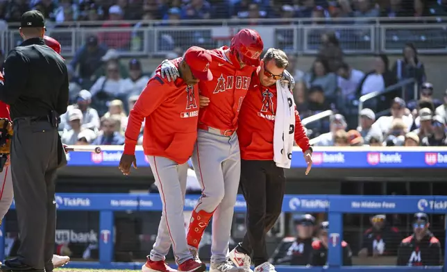 Los Angeles Angels' Nolan Schanuel, center, is helped off the field after fouling off a ball into his knee on a pitch by Minnesota Twins pitcher Simeon Woods Richardson during the fourth inning of a baseball game, Saturday, April 26, 2025, in Minneapolis. (AP Photo/Craig Lassig)