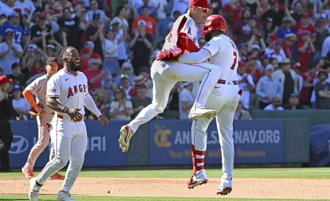 Los Angeles Angels outfielder Jo Adell, right, celebrates his three-run double to win the game against the San Francisco Giants with Los Angeles Angels catcher Logan O'Hoppe (14) and Los Angeles Angels third base Luis Rengifo, left, during the ninth inning of a baseball game Sunday, April 20, 2025, in Anaheim, Calif. (AP Photo/Wally Skalij)