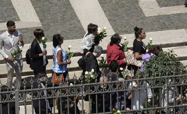 Faithful holding white roses wait for the burial ceremony of Pope Francis at St. Mary Major Basilica in Rome, Saturday, April 26, 2025. (AP Photo/Luca Bruno)