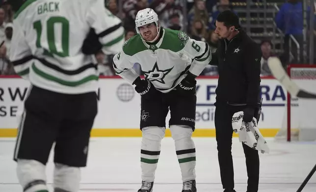 Dallas Stars defenseman Lian Bichsel, center, is helped to the team box after being injured in the second period of Game 3 of an NHL hockey first-round playoff series against the Colorado Avalanche Wednesday, April 23, 2025, in Denver. (AP Photo/David Zalubowski)