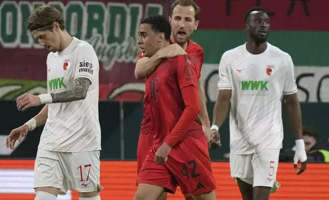 Bayern's Harry Kane hugs Jamal Musiala after he scored during the German Bundesliga soccer match between Augsburg and Bayern Munich in Augsburg, Friday, April 4, 2025. (AP Photo/Matthias Schrader)