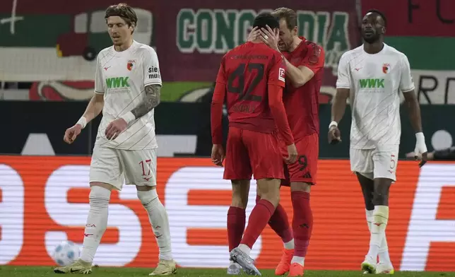 Bayern's Harry Kane hugs Jamal Musiala after he scored during the German Bundesliga soccer match between Augsburg and Bayern Munich in Augsburg, Friday, April 4, 2025. (AP Photo/Matthias Schrader)