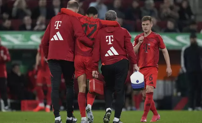 Bayern's Jamal Musiala is helped off the pitch during the German Bundesliga soccer match between Augsburg and Bayern Munich in Augsburg, Friday, April 4, 2025. (AP Photo/Matthias Schrader)