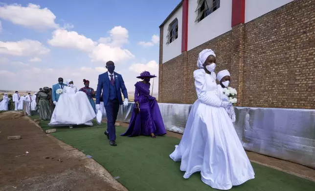 A man with his wife and two of his brides walk, during mass Easter weddings for 3,000 people, some polygamous, at the International Pentecost Holiness Church in Heidelberg, east of Johannesburg, South Africa, Sunday, April 20, 2025. (AP Photo/Themba Hadebe)