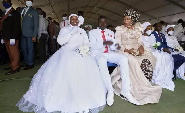 Joseph Manganye, centre, with his wife Tshidi Manganye, right, and his bride Sophy Manganye sit inside a marquee ahead of the mass Easter weddings for 3,000 people, some polygamous, at the International Pentecost Holiness Church in Heidelberg, east of Johannesburg, South Africa, Sunday, April 20, 2025. (AP Photo/Themba Hadebe)