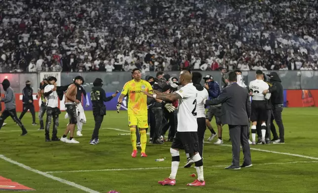 Arturo Vidal of Chile's Colo Colo talks to fans who invaded the field during a Copa Libertadores Group E soccer match between Chile's Colo Colo and Brazil's Fortaleza at the Monumental stadium in Santiago, Chile, Thursday, April 10, 2025. (AP Photo/Esteban Felix)