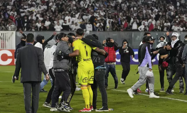 Goalkeeper Brayan Cortes of Chile's Colo Colo confronts fans who invaded the field during a Copa Libertadores Group E soccer match against Brazil's Fortaleza at the Monumental stadium in Santiago, Chile, Thursday, April 10, 2025. (AP Photo/Esteban Felix)