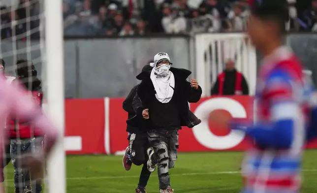 Fans invade the field during a Copa Libertadores Group E soccer match between Chile's Colo Colo and Brazil's Fortaleza at the Monumental stadium in Santiago, Chile, Thursday, April 10, 2025. (AP Photo/Esteban Felix)