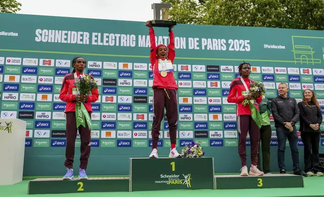 From left, second-placed Dera Dida of Ethiopia, winner Bedatu Hirpa of Ethiopia and third-placed Angela Tanui of Kenya pose on the podium of the Paris marathon, in Paris, Sunday, April 13, 2025. (AP Photo/Aurelien Morissard)