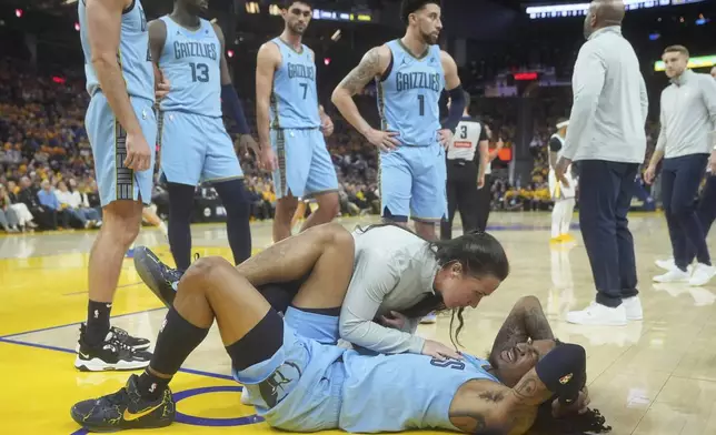 Memphis Grizzlies guard Ja Morant, bottom, reacts after hitting the floor during the second half of an NBA play-in tournament basketball game against the Golden State Warriors in San Francisco, Tuesday, April 15, 2025. (AP Photo/Jeff Chiu)