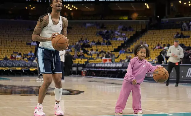 Memphis Grizzlies guard Ja Morant warms up with his daughter Kaari Morant before an NBA play-in tournament basketball game against the Dallas Mavericks, Friday, April 18, 2025, in Memphis, Tenn. (AP Photo/George Walker IV)